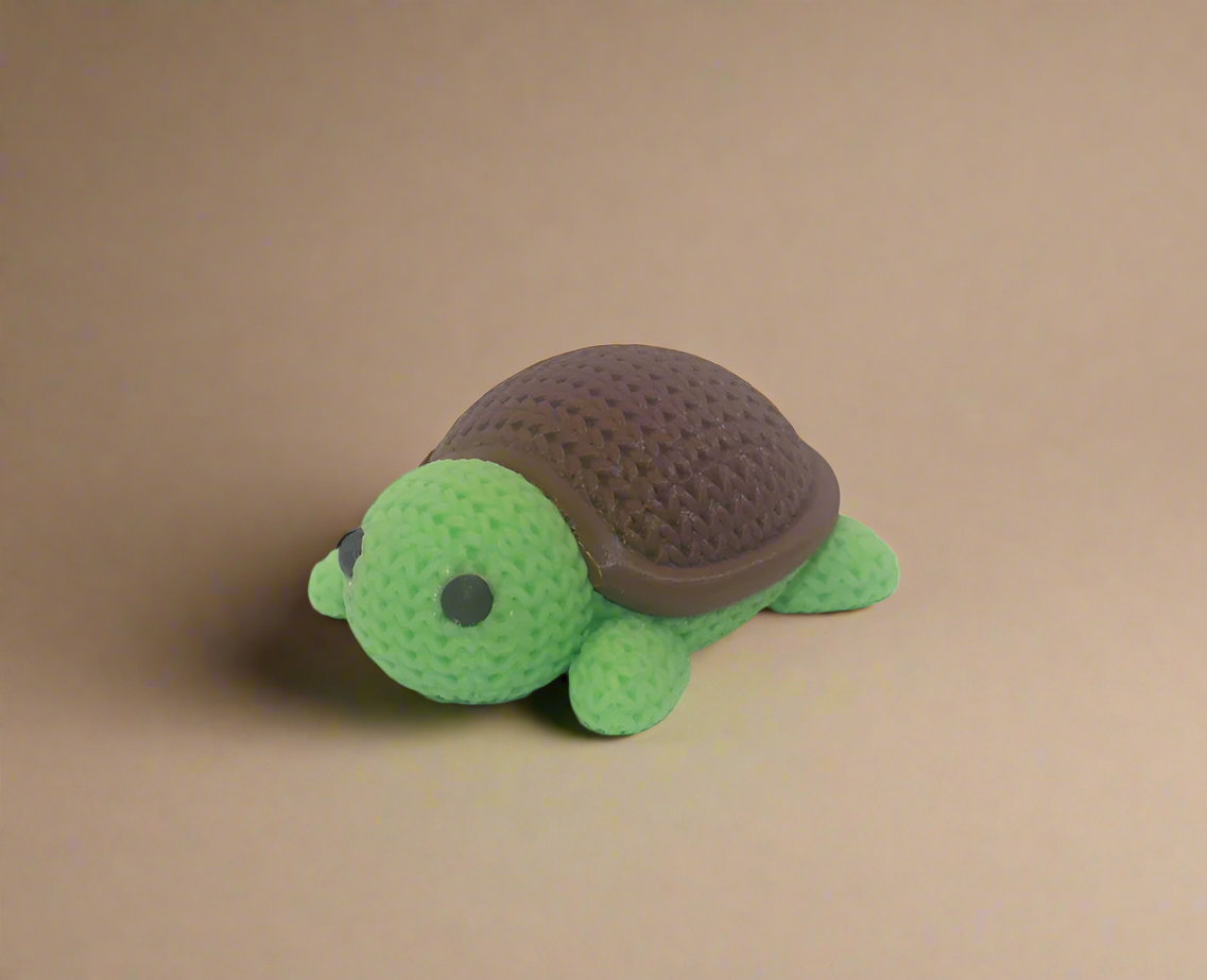 Crocheted turtle toy with a brown shell on a white background