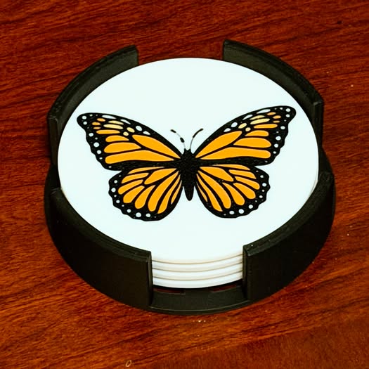 Butterfly design on a round white coaster with black holder