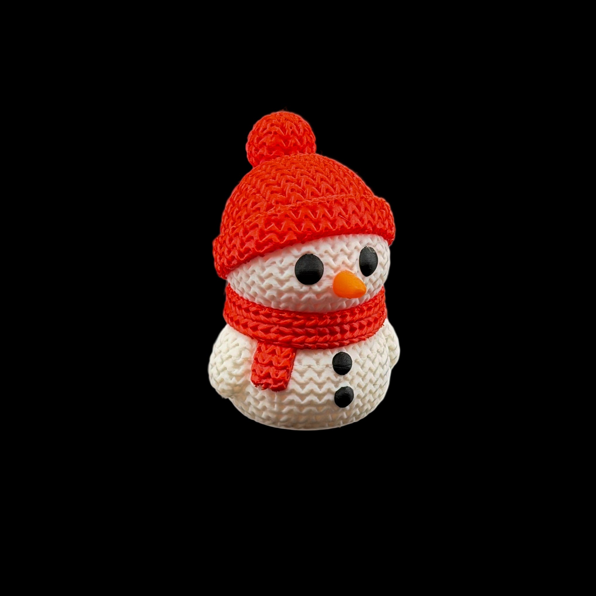 Cute snowman figurine wearing a red knit hat with pom-pom and matching scarf, featuring black button eyes, a small orange carrot nose, and black button details.